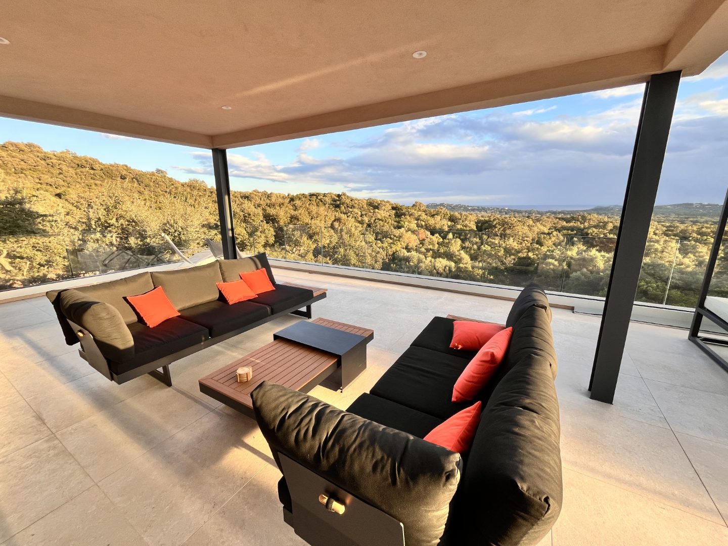 La terrasse couverte du niveau haut, ses banquettes et la vallée en contrebas.